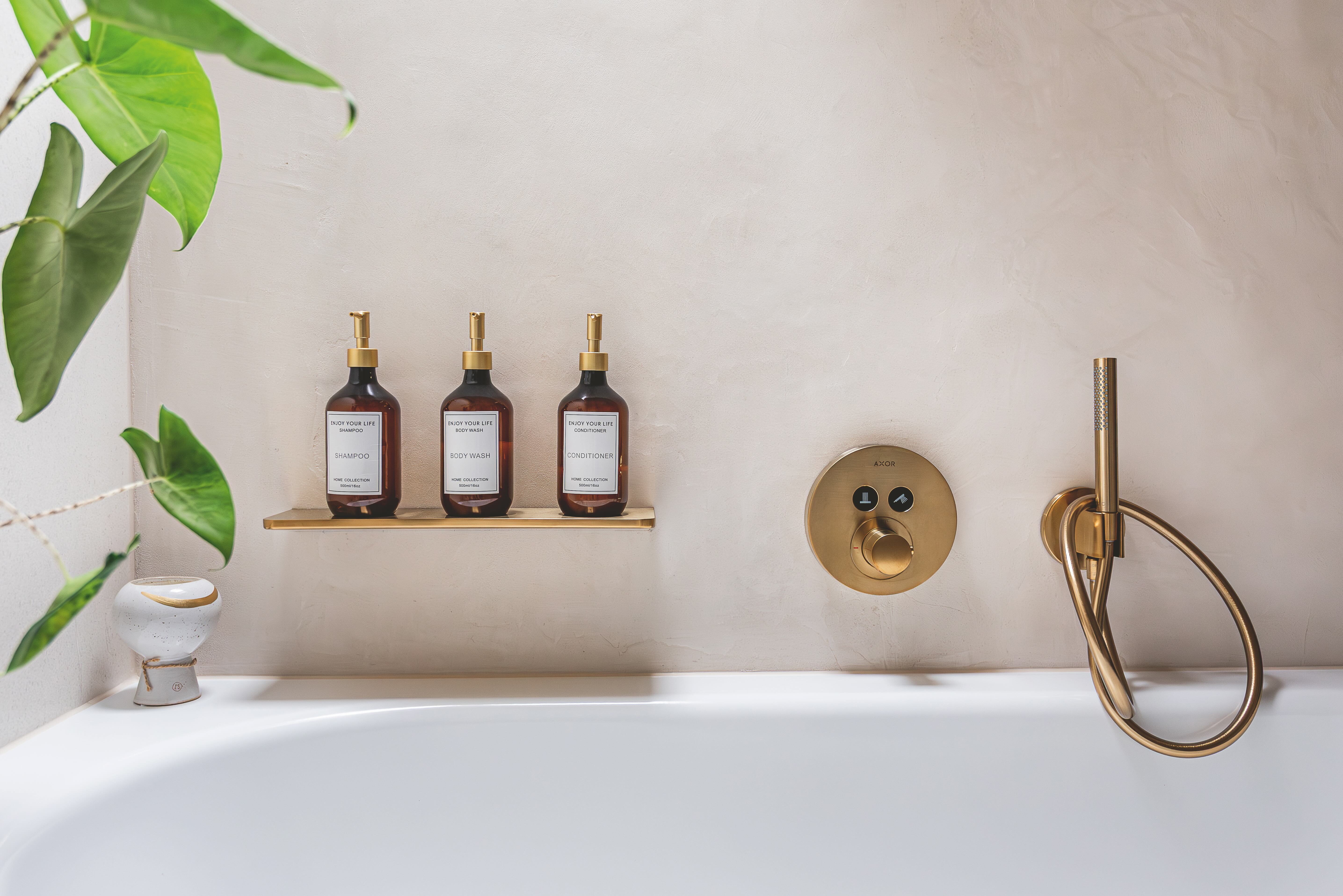 Minerale betonstuc zorgt voor een serene en natuurlijke uitstraling. De Axor kranen maken het geheel af met de warm-goud geborstelde kraankleur en accessoires