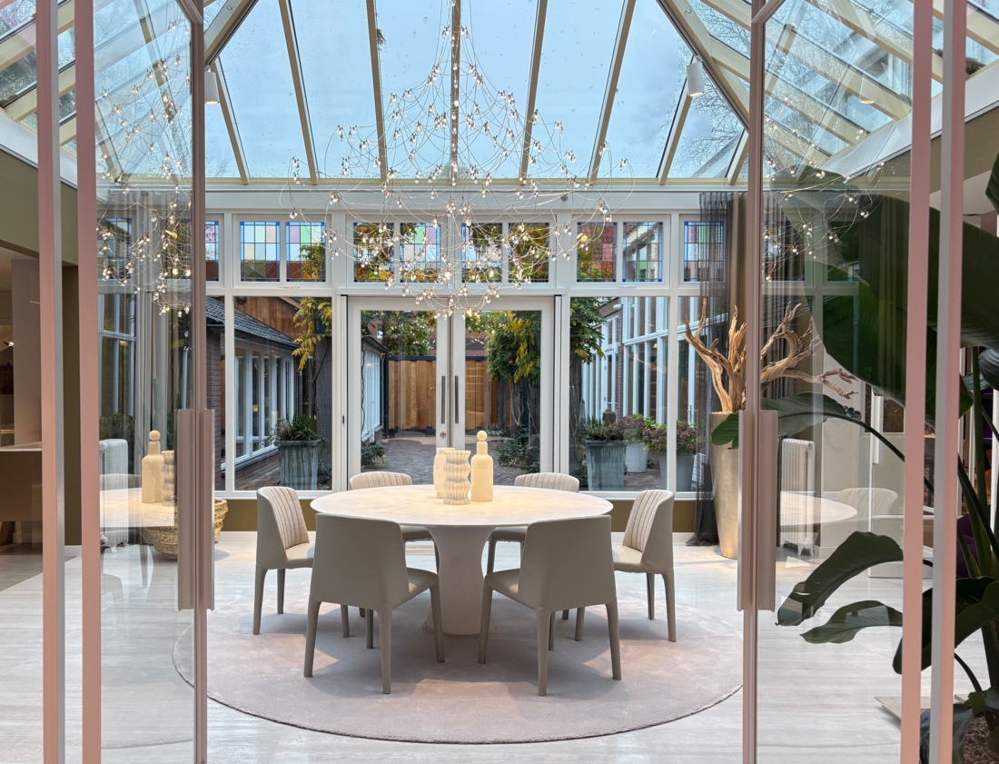 Studio Bloemex De open en transparante serre vormt het hart van de Bloemex showroom: een lichte, verfijnde ruimte waarin de ronde tafel van Alinea en de Bicolette stoelen van Giorgetti elegant samenkomen. Boven deze setting zweeft de Crystal Galaxy lamp van Quasar, die met zijn sculpturale uitstraling het geheel een tijdloze allure geeft