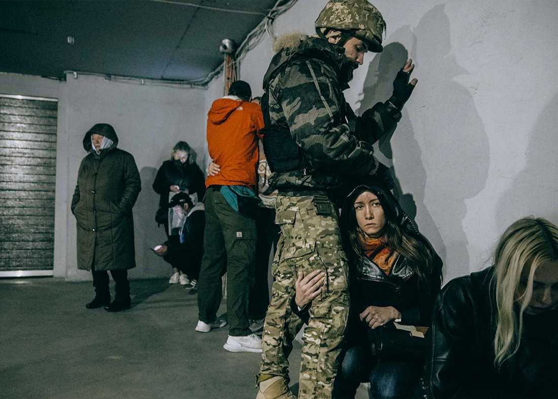 A soldier protects a woman in an underground parking lot near the drone strike in Kyiv on 17 October, 2022 © Julia Kochetova.